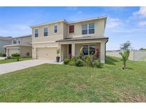 Two-story home featuring a two-car garage, manicured lawn, and colorful flowers, offering classic curb appeal at 30936 Summer Sun Loop, Wesley Chapel, FL 33545