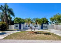 Charming single-story home featuring a well-manicured lawn, circular driveway, and mature palm trees at 10367 109Th Ave, Largo, FL 33773