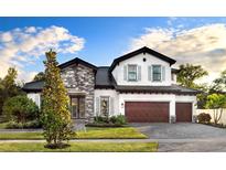 Beautiful two-story home showcasing stone accents, three-car garage, lush lawn, and inviting front entrance at 125 Hidden Estates Ct, Brandon, FL 33511