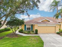 Charming one-story home with a well-manicured lawn, mature trees, and a two-car garage at 2218 Brookfield Greens Cir # 82, Sun City Center, FL 33573