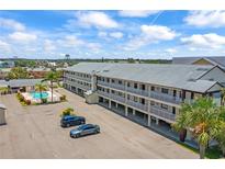 Three story apartment building featuring balconies, a pool, parking and tropical landscaping at 340 Causeway Blvd # 104, Dunedin, FL 34698