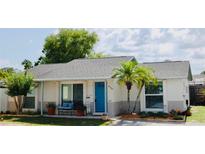 Charming single-story home boasts a bright blue front door, lush landscaping, and a welcoming front porch with seating at 9128 Suffield Ct, Tampa, FL 33615