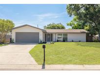 Charming single-story home with a well-manicured lawn, grey trim and a two-car garage on a sunny day at 11296 115Th St, Largo, FL 33778