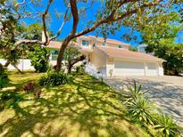 Inviting home featuring a three-car garage, charming landscaping, and a beautiful stairway entrance at 1330 Belcher Dr, Tarpon Springs, FL 34689
