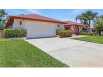Charming single-story home featuring an attached two-car garage, red roof, and manicured landscaping at 14168 Fennsbury Dr, Tampa, FL 33624