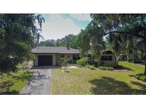 A charming single-story home with a well-maintained front yard and an attached garage, framed by mature trees at 34389 Orchid Pkwy, Ridge Manor, FL 33523