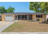 Charming single-story home with a screened front porch, one-car garage, and well-maintained front lawn at 5027 Overton Dr, New Port Richey, FL 34652