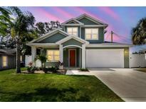 Charming two-story home featuring a landscaped yard and a welcoming orange front door at 511 Roanoke St, Dunedin, FL 34698