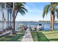 Beautiful waterfront view of the boat dock with boats, lush tropical landscaping, and waterway at 5225 Brighton Shore Dr, Apollo Beach, FL 33572