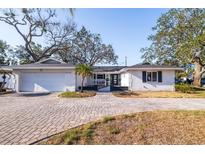 Charming single-story home featuring a white brick facade, well-manicured landscaping, and a paved driveway at 8296 33Rd N Ave, St Petersburg, FL 33710