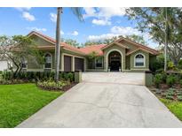 Charming single-story home featuring lush landscaping, a terracotta roof, and an attached two-car garage at 9075 Waterash N Ln, Pinellas Park, FL 33782