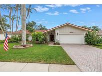 Charming single-story home with a well-manicured lawn, mature trees, and brick driveway at 9674 104Th Ave, Largo, FL 33773