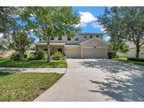Beautiful two-story home featuring a three-car garage, a manicured lawn, and mature trees at 10833 Breaking Rocks Dr, Tampa, FL 33647