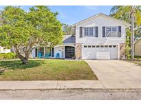 Charming two-story home with a well-manicured lawn and a two-car garage on a sunny day at 12222 Meadowbrook Ln, Hudson, FL 34667