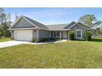 Charming single-story home featuring stone accents, a two-car garage, and a well-manicured lawn at 13227 Quigley Ave, Weeki Wachee, FL 34614