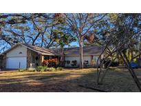 Charming single-story home with mature trees, stone accents, and attached two-car garage at 2033 Aaron Pl, Clearwater, FL 33760