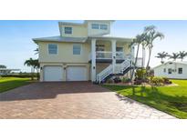 Charming two-story home with palm trees, a two-car garage and a welcoming staircase leading to the entrance at 24197 Treasure Island Blvd., Punta Gorda, FL 33955