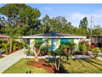 Charming home featuring bright shutters, lush tropical landscaping, and a well-manicured lawn at 2479 Trade Winds Dr, Dunedin, FL 34698