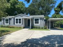 Charming single-story home with well-maintained landscaping, gray exterior, and a concrete driveway and carport at 2709 S Manhattan Ave, Tampa, FL 33629
