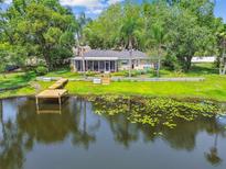 Waterfront home featuring a lush yard, dock, screened lanai, and beautiful lake views at 3366 Clover Leaf Ln, Land O Lakes, FL 34639