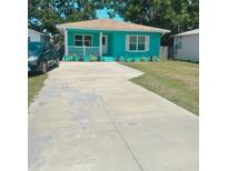 Charming aqua home features a quaint front porch, a long driveway and beautiful landscaping at 4811 Haines N Rd, St Petersburg, FL 33714