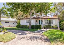 Charming single-story home featuring a brick driveway, lush landscaping, and a well-maintained lawn at 6114 7Th S Ave, Gulfport, FL 33707