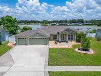 Well-maintained home showcasing a three-car garage, beautiful landscaping, and serene lake view at 6425 Clair Shore Dr, Apollo Beach, FL 33572