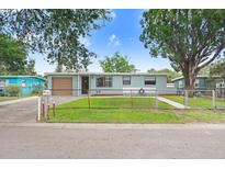 Charming single-story home with a fenced front yard and a well-maintained lawn, complemented by mature trees and a blue sky at 660 11Th N Ave, Safety Harbor, FL 34695