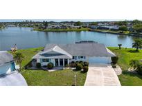 Waterfront property features a well-manicured lawn and an attached two-car garage at 1009 Andover Cir, Sun City Center, FL 33573