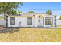 Charming single-story home with a manicured lawn and freshly painted white facade and decorative black accents at 1128 Eau Claire Cir, Tampa, FL 33619
