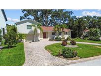 Charming home featuring a brick driveway, lush landscaping, and mature palm trees at 1238 Monterey Ne Blvd, St Petersburg, FL 33704