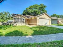 Charming single-story home with a well-manicured lawn, attached two-car garage and mature shade tree at 1517 Gunsmith Dr, Lutz, FL 33559