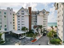 Beautiful beachside condo with a charming white facade, lush landscaping, and convenient covered parking at 1586 Gulf Blvd # 2502, Clearwater, FL 33767