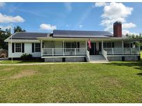 Charming single-story home featuring a welcoming front porch and solar panels for energy efficiency at 17430 Spring Valley Rd, Dade City, FL 33523