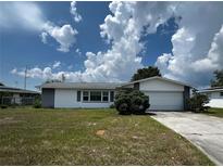 Charming single-story home featuring an attached garage, mature landscaping, and a well-maintained front yard at 2195 Academy Dr, Clearwater, FL 33764