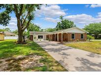 Charming single-story brick home with a long driveway, mature landscaping, and a covered front porch at 509 Falmouth St, Temple Terrace, FL 33617