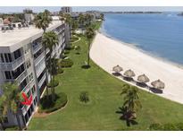 An aerial view of the condo building on the beach with green lawn, sand and beach umbrellas at 5701 Bahia Del Mar Cir # 108, St Petersburg, FL 33715