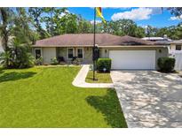 Charming single-story home featuring a manicured lawn, stone accents, and an attached two-car garage at 7818 Holiday Dr, Spring Hill, FL 34606