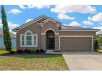 Charming single-story home featuring a well-manicured lawn and neutral color palette, with a two-car garage at 7822 Atwood Dr, Wesley Chapel, FL 33545