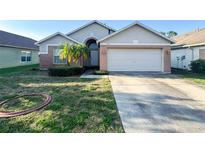 Charming single-story home featuring a two-car garage, brick accents, and a well-maintained front yard at 9735 Riverchase Dr, New Port Richey, FL 34655