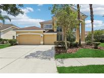 Two-story home with a tan exterior, attached two car garage, and mature landscaping at 10205 Deercliff Dr, Tampa, FL 33647