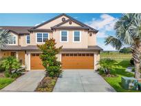 Charming townhome featuring a two-car garage, manicured landscaping and serene water views at 11291 Cay Spruce Way, San Antonio, FL 33576