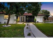 Charming home featuring a walkway lined with white stones, lush green lawn, and mature landscaping at 2306 S San Jose Cir, Tampa, FL 33629