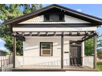 Charming home exterior features a covered porch with pergola, a black front door and white picket fence at 2315 E 12Th Ave, Tampa, FL 33605