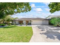 Charming single-story home featuring a tile roof, manicured lawn, and lush landscaping at 2900 Sandpiper Pl, Clearwater, FL 33762