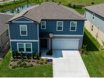 Two-story home features an attached two-car garage, beautiful blue siding, and landscaped front yard at 35100 Brackett Bnd, Zephyrhills, FL 33541