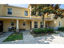 Inviting townhome exterior featuring a covered porch, manicured landscaping, and classic architectural details at 37712 Aaralyn Rd, Zephyrhills, FL 33542