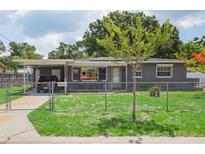 Charming single-story home featuring a fenced front yard, covered parking and beautiful landscaping at 4512 S Lois Ave, Tampa, FL 33611