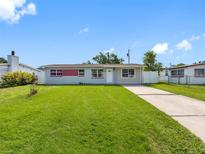 Charming single-story home with a well-manicured lawn and a long driveway under a bright sky at 4925 Murray Hill Dr, Tampa, FL 33615