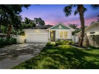 Charming home showcasing a manicured lawn, stone accents, and a welcoming two-car garage under colorful twilight skies at 527 Bay St, Dunedin, FL 34698
